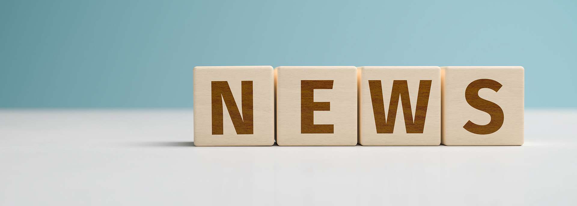 Wooden letters form the word "NEWS" on a light background.