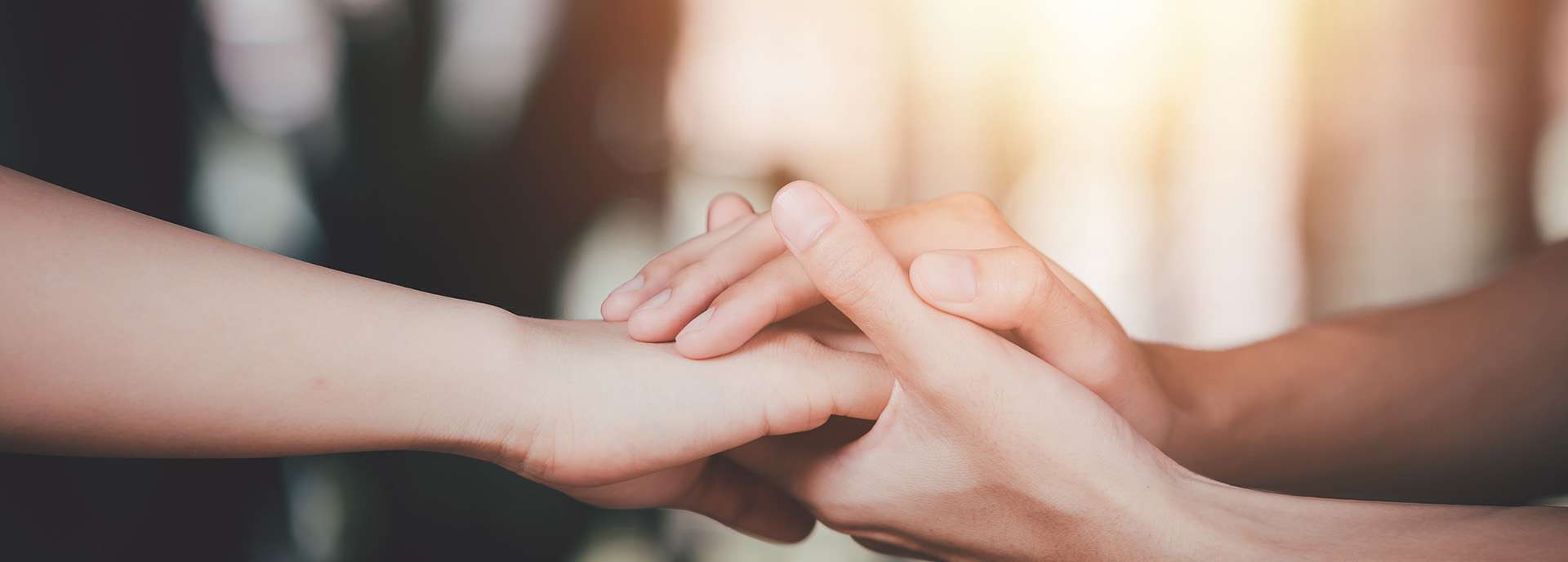 Two hands gently touching symbolize support and connection in warm light.