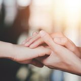 Two hands gently touching symbolize support and connection in warm light.