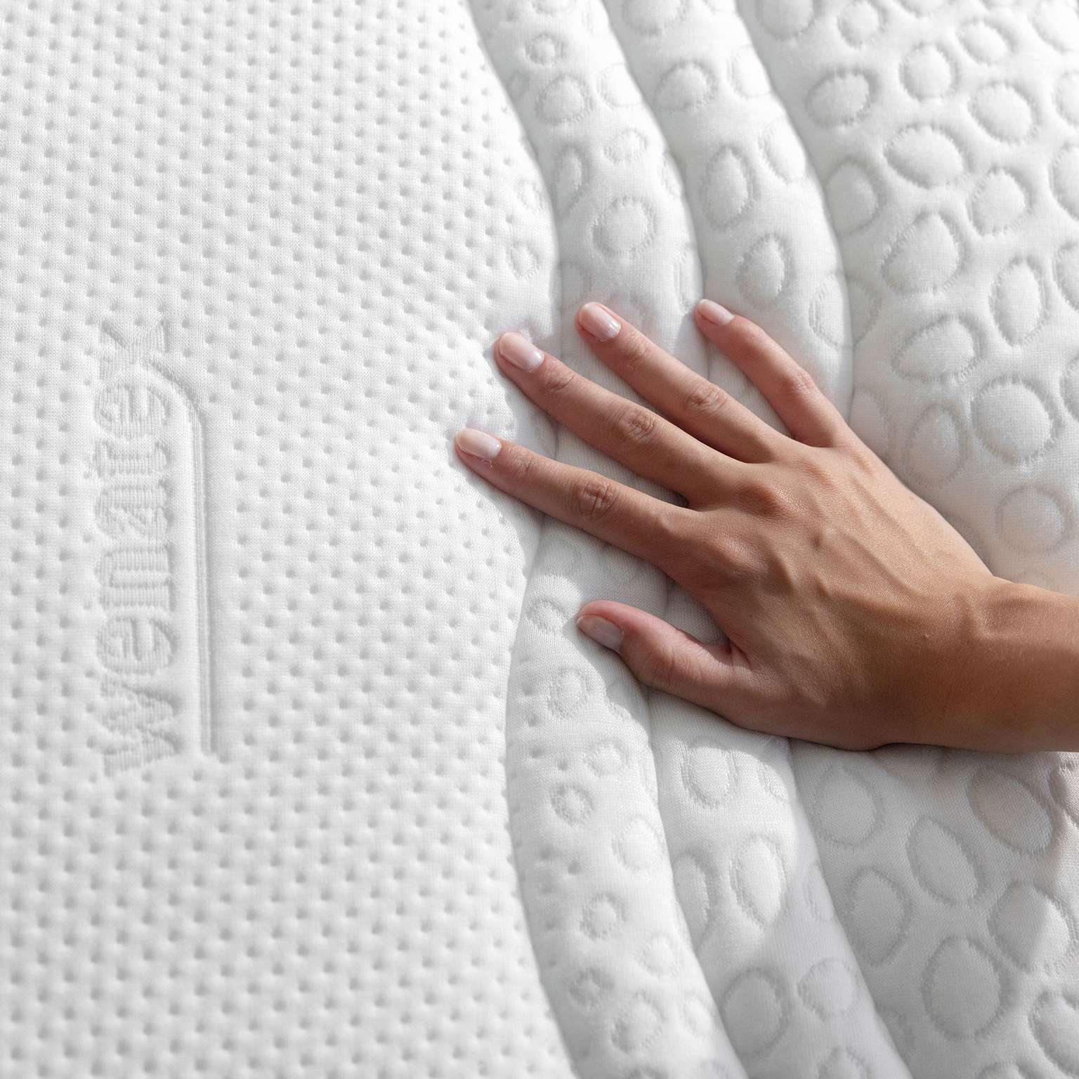 Hand, die über den Matratzenbezug von Wenatex Comfort Plus gleitet, zeigt die Struktur und Qualität des Materials.