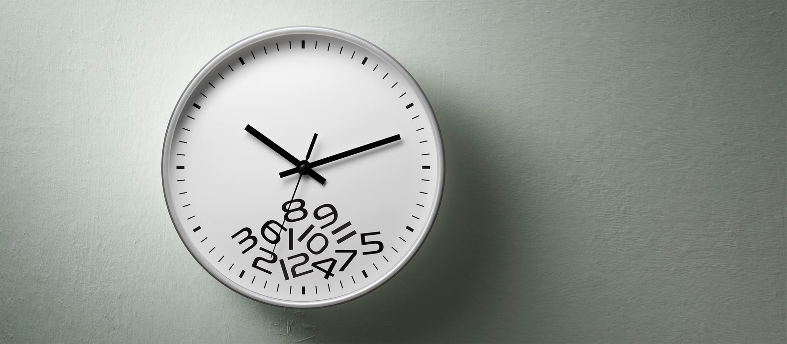 Wanduhr mit unkonventioneller Ziffernplatzierung auf grauem Hintergrund.