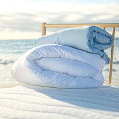 Bettdecke und Kissen von Wenatex auf einem Bett am Strand mit Meerblick.
