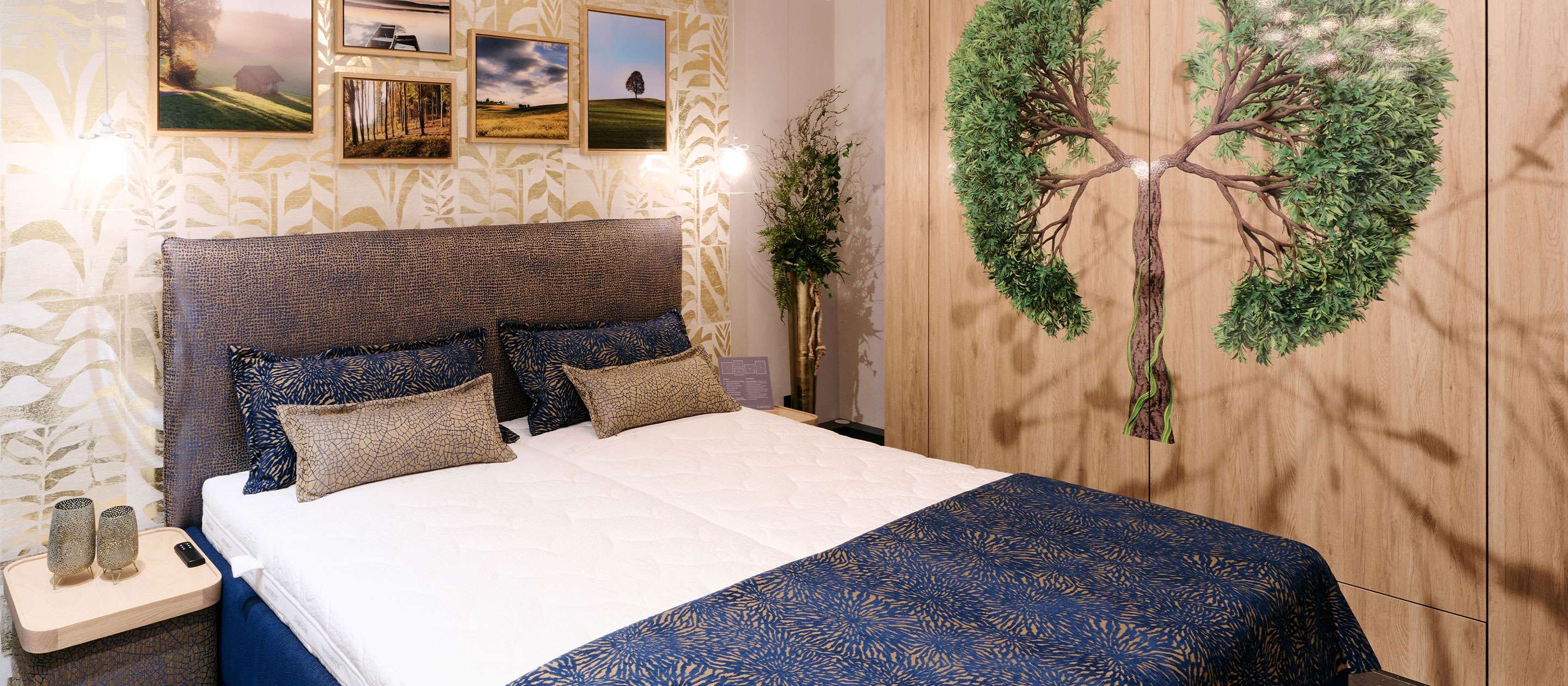 Interior view of a bedroom featuring a double bed, decorative pillows, and tree motif wall design.