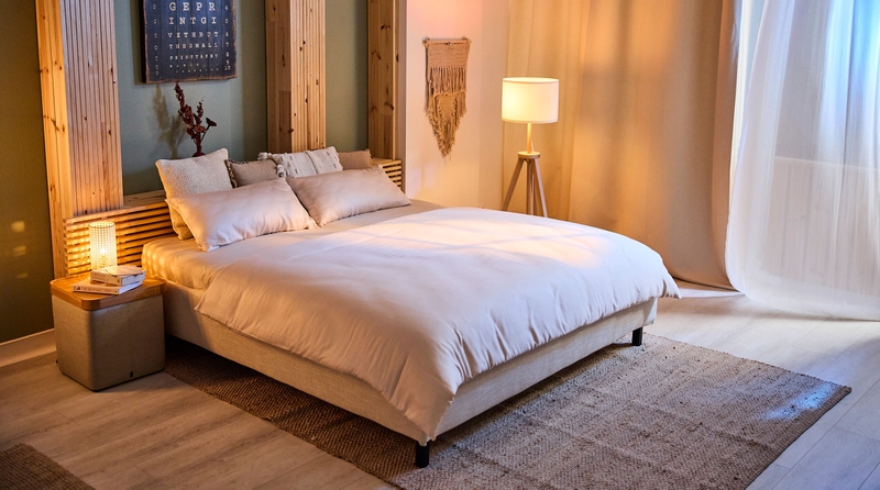 Gemütliches Schlafzimmer mit Bett, Kissen und Bettdecke in warmen Farbtönen.